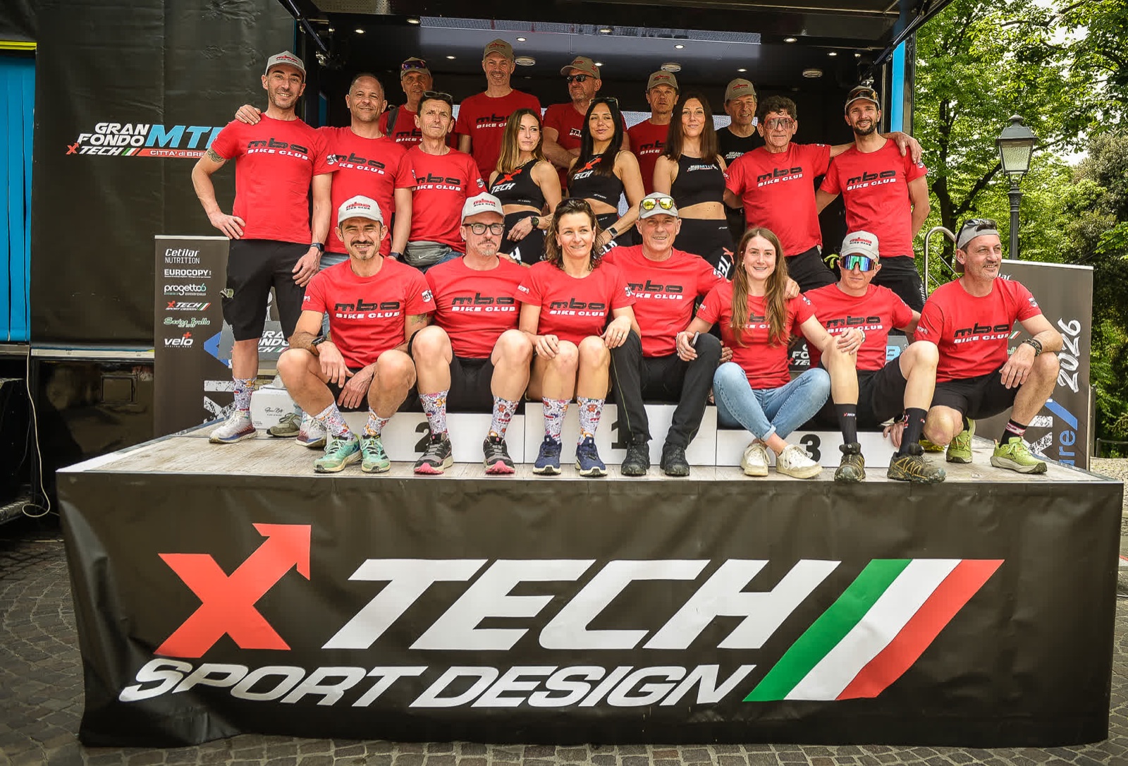 Il gruppo di atleti e volontari dell'ASD MBO bike club in maglia sociale rossa, sul podio della Gran Fondo MTB XTech Città di Brescia 2026.